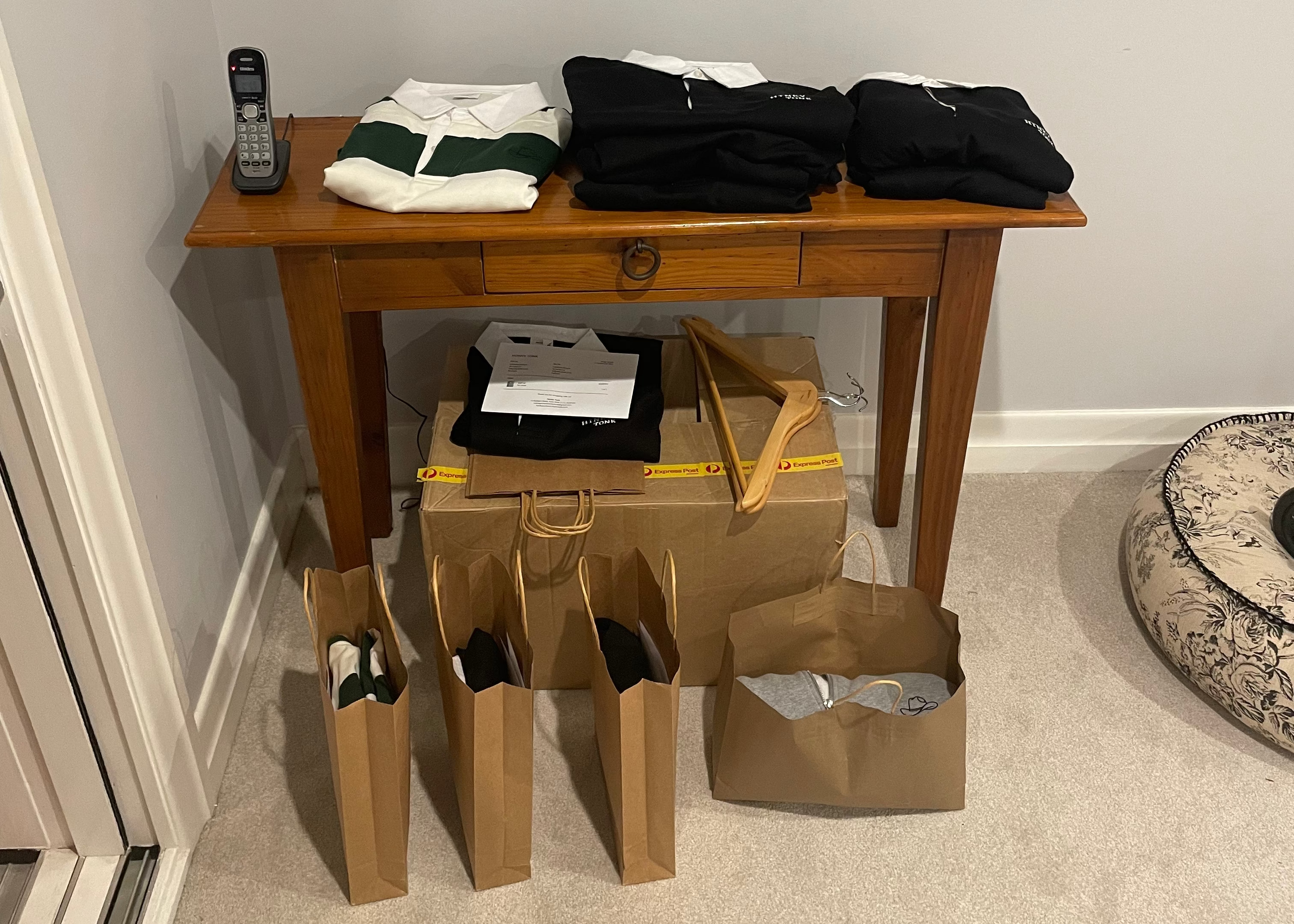 Wooden table with folded clothes and open cardboard boxes in a room.